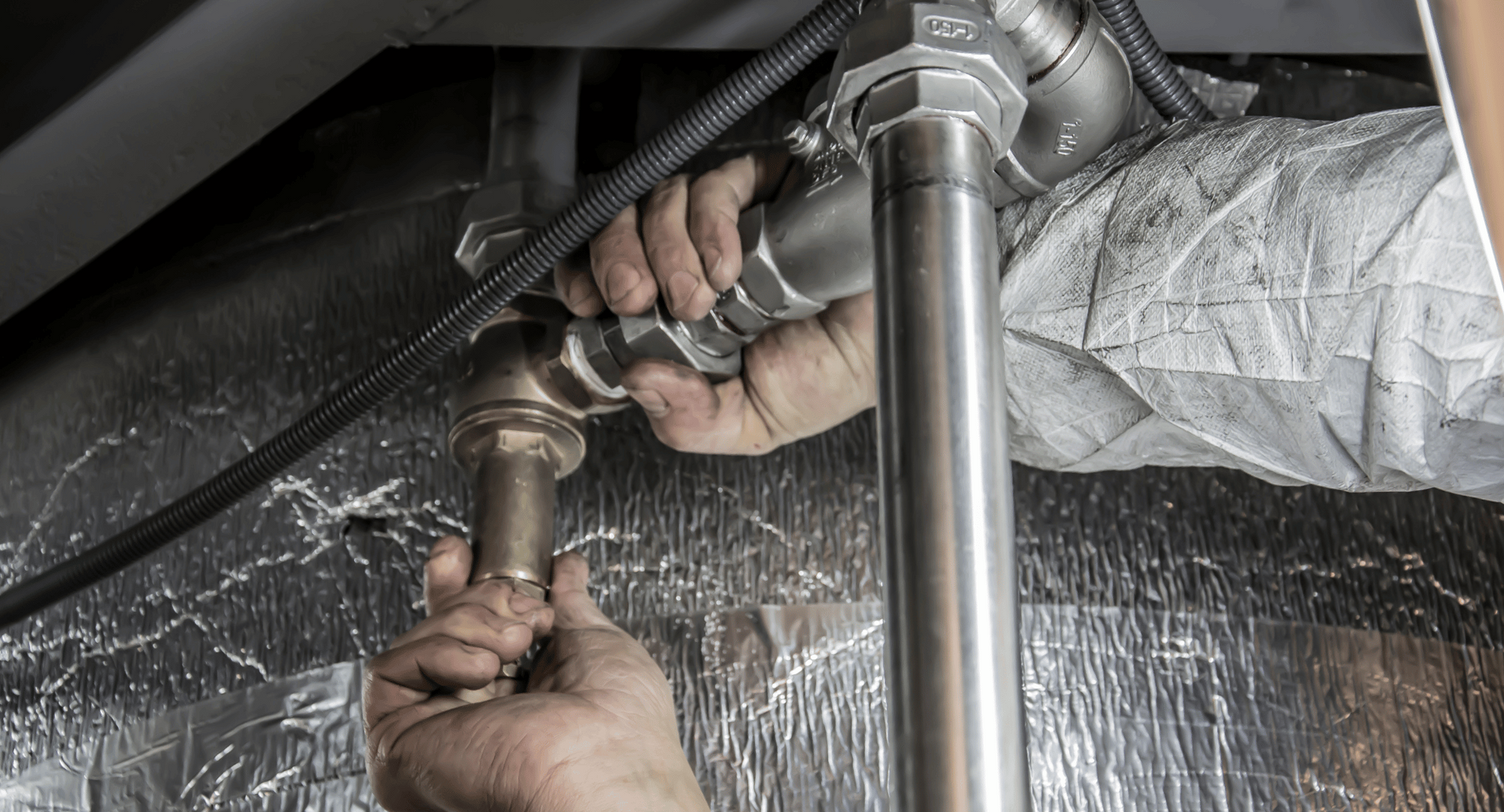 A plumber is fixing a sink pipe with a wrench.