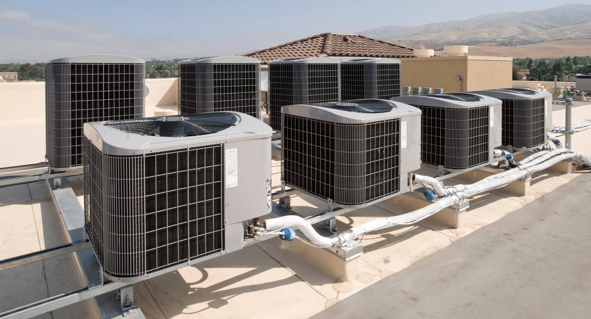 A row of air conditioners are sitting on top of a building.