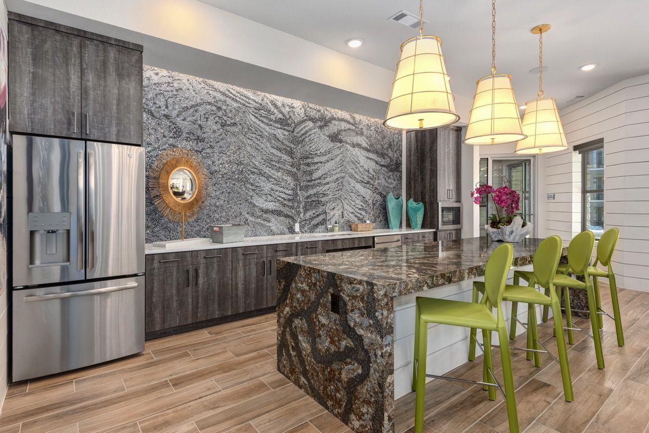 Modern kitchen in a model unit with granite island, stainless steel appliances, and lime green bar stools.