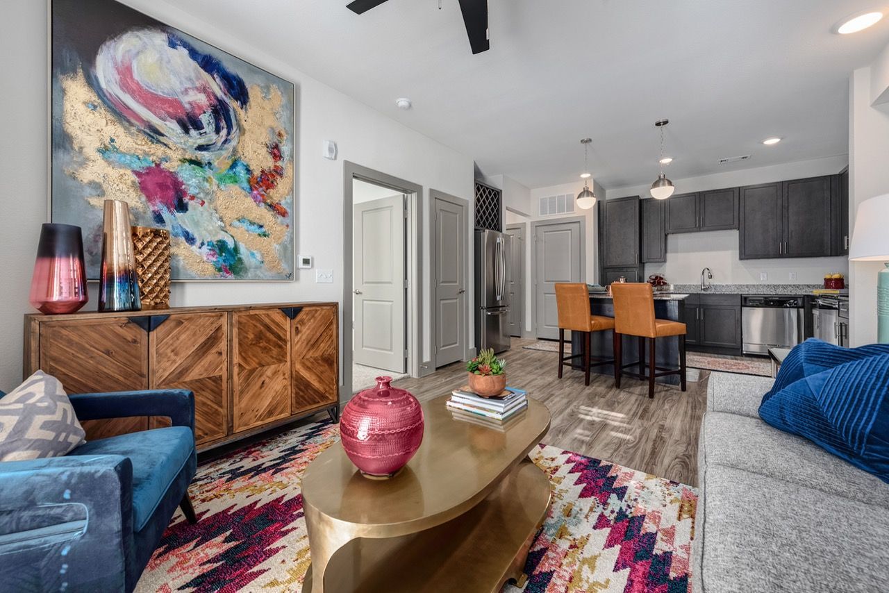 Open-concept apartment living area with colorful abstract art and a modern kitchen.