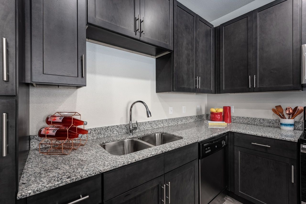 Modern kitchen with dark wood cabinets, granite countertops, and a double-basin sink.