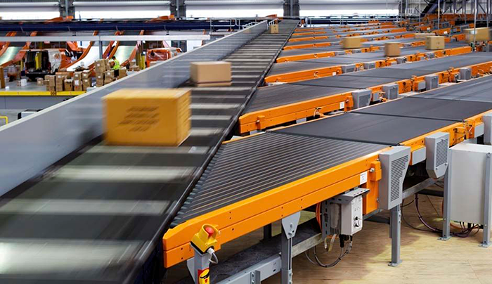 A box is moving down a conveyor belt in a warehouse.