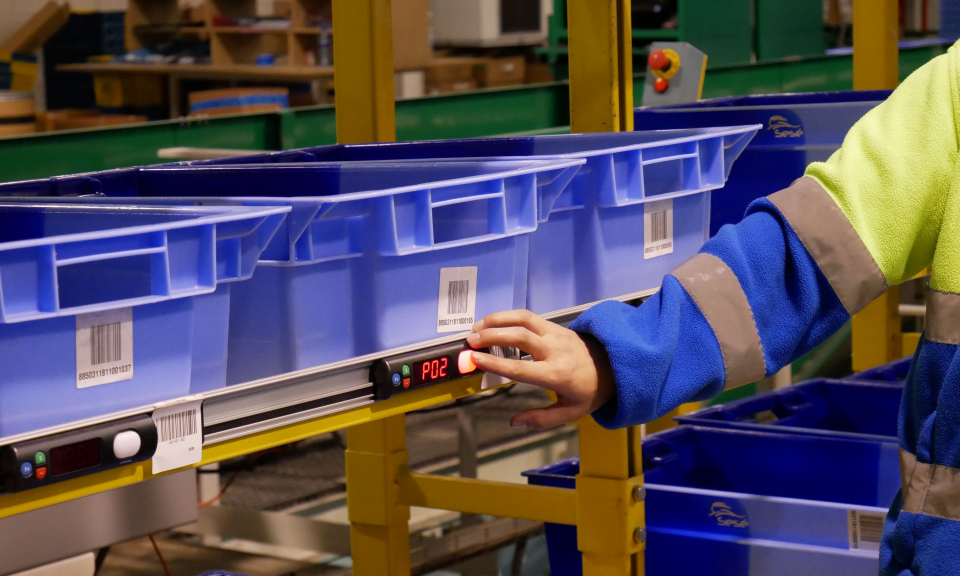 A person in a blue and yellow safety vest is working in a warehouse.