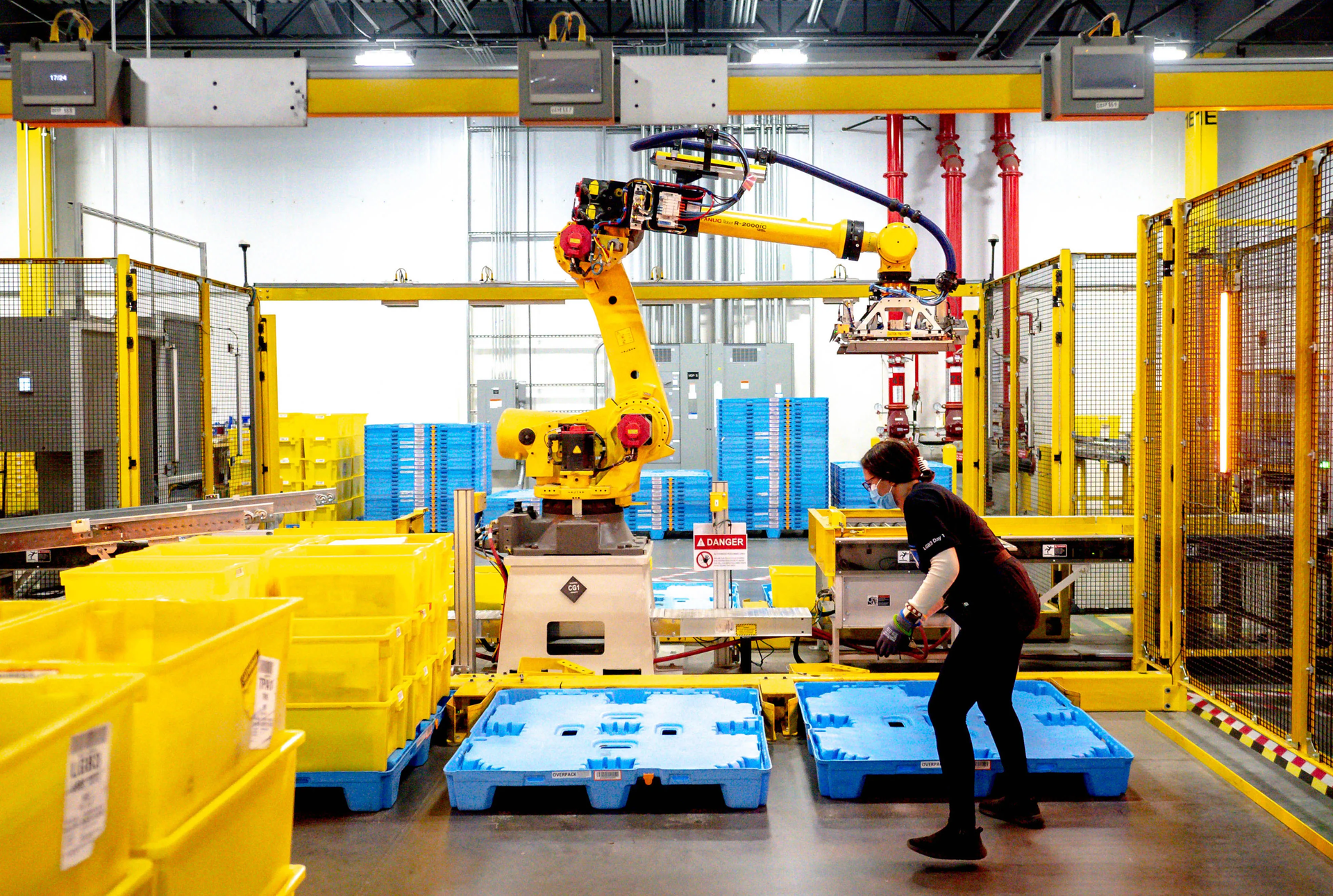 A man is working on a robotic arm in a warehouse.