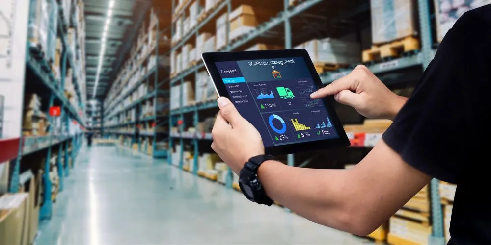 A man is using a tablet in a warehouse.
