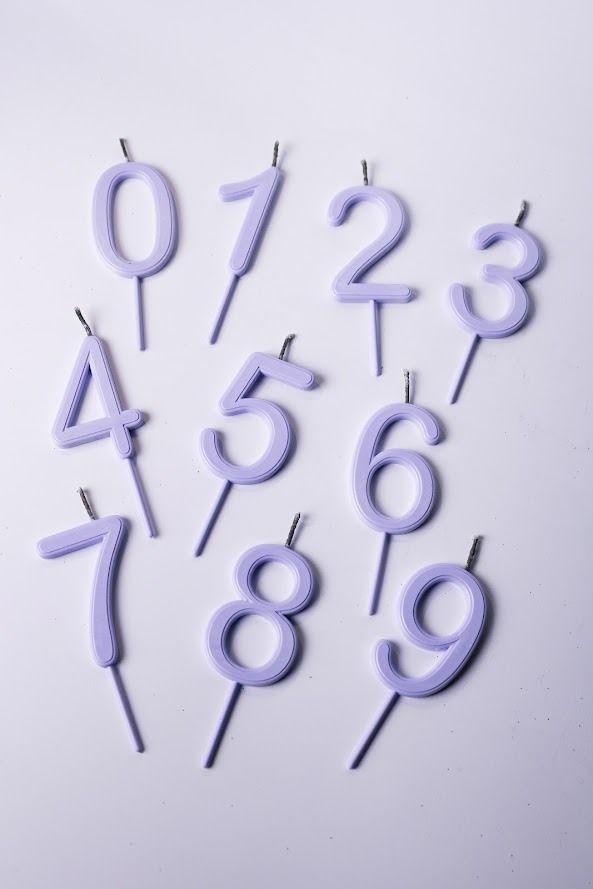 Velas numeradas de color lavanda del 0 al 9 dispuestas sobre un fondo claro.