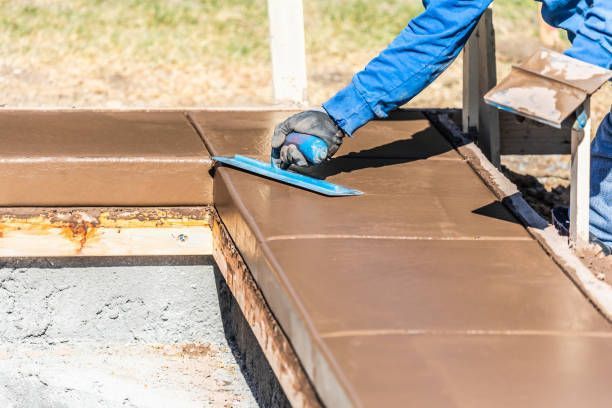 Swimming pool renovation contractor smoothing fresh cement for a residential pool project.