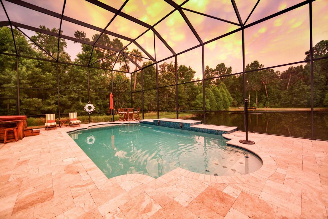 A large swimming pool is surrounded by a screened in area.