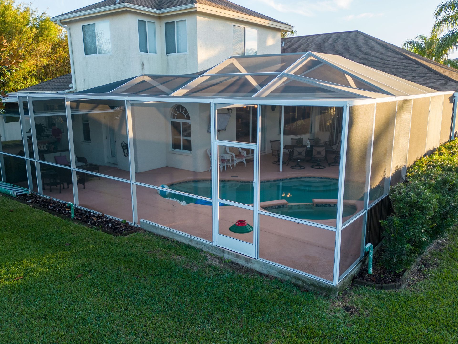 Screened-in backyard pool area beside a two-story house.