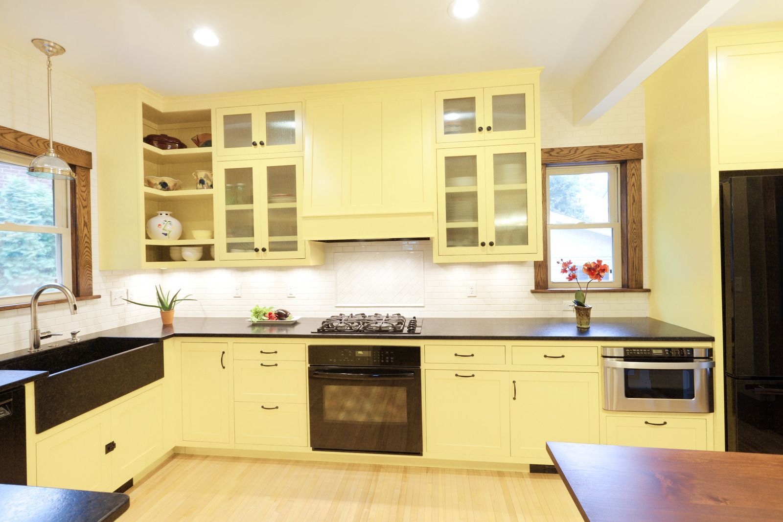 A kitchen with yellow cabinets and black counter tops