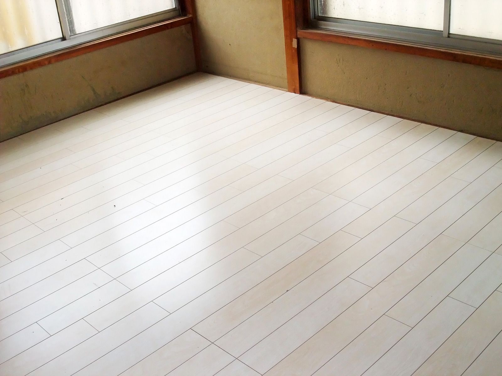 A room with a white wooden floor and two windows