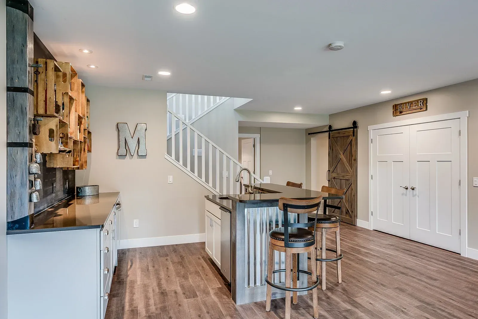 A kitchen with a bar and stools in a basement.