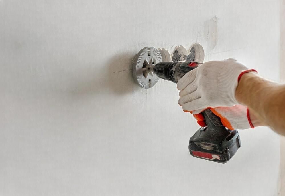 A person is using a drill to drill a hole in a wall.