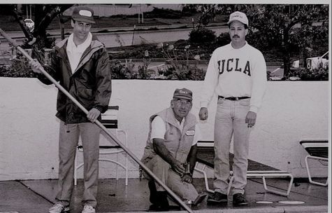 A man wearing a ucla shirt is standing next to two other men