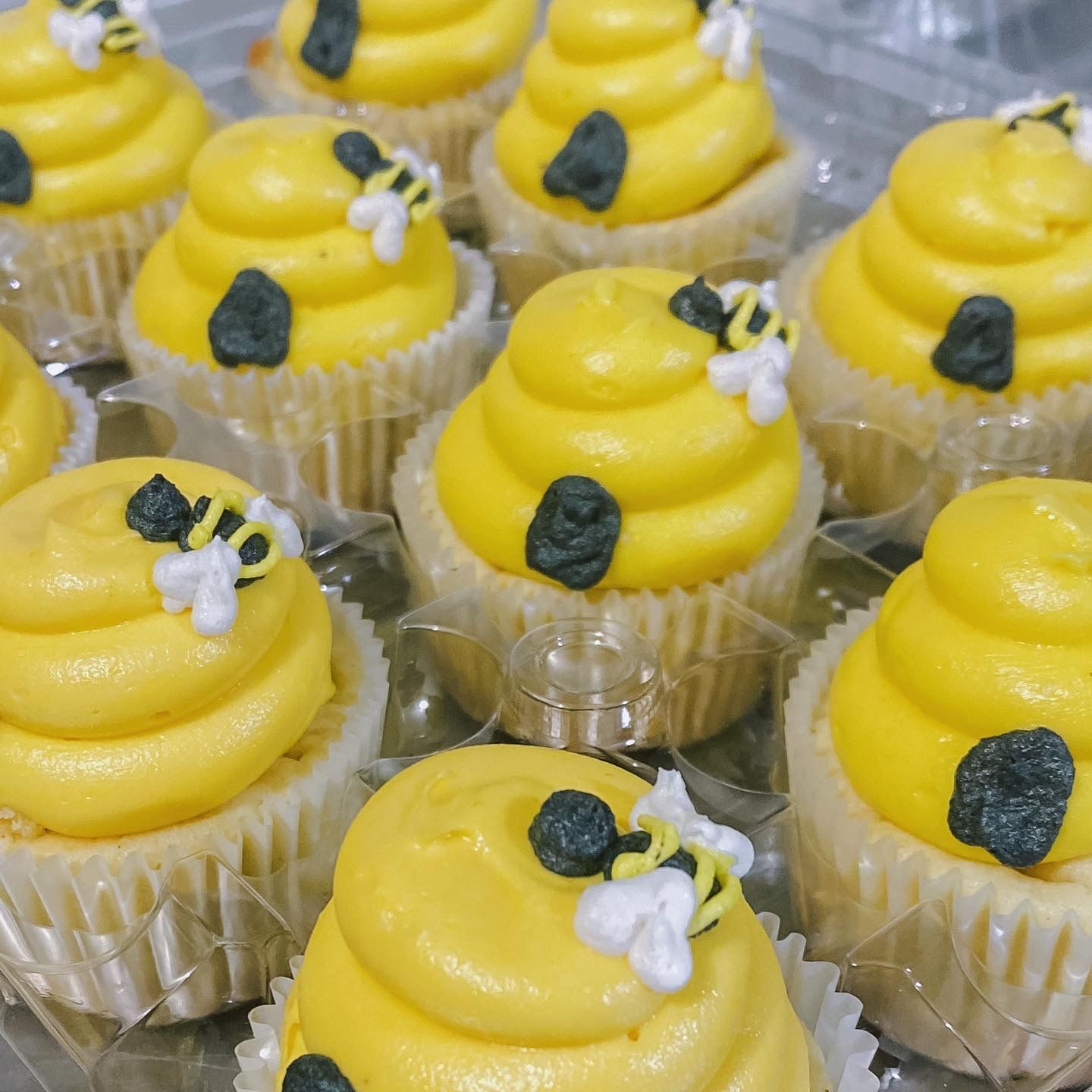 A bunch of cupcakes with yellow frosting and bees on them