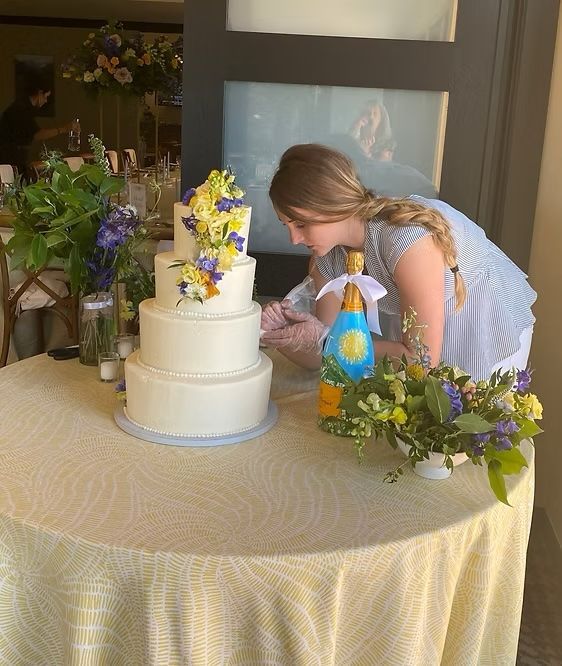 A woman is working on a wedding cake on a table