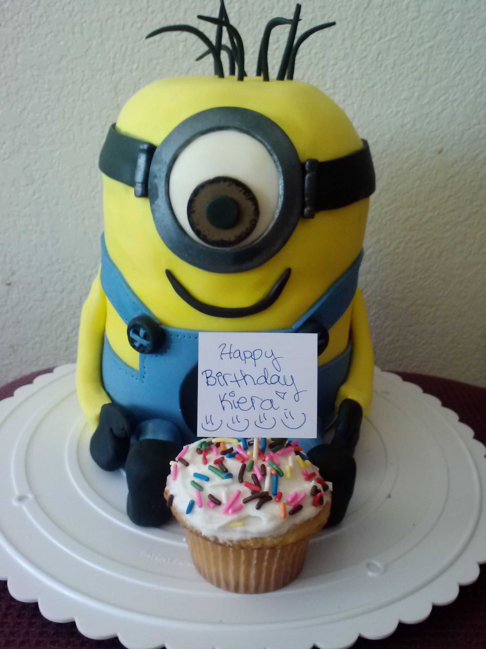 A cake with a minion on it and a cupcake with sprinkles