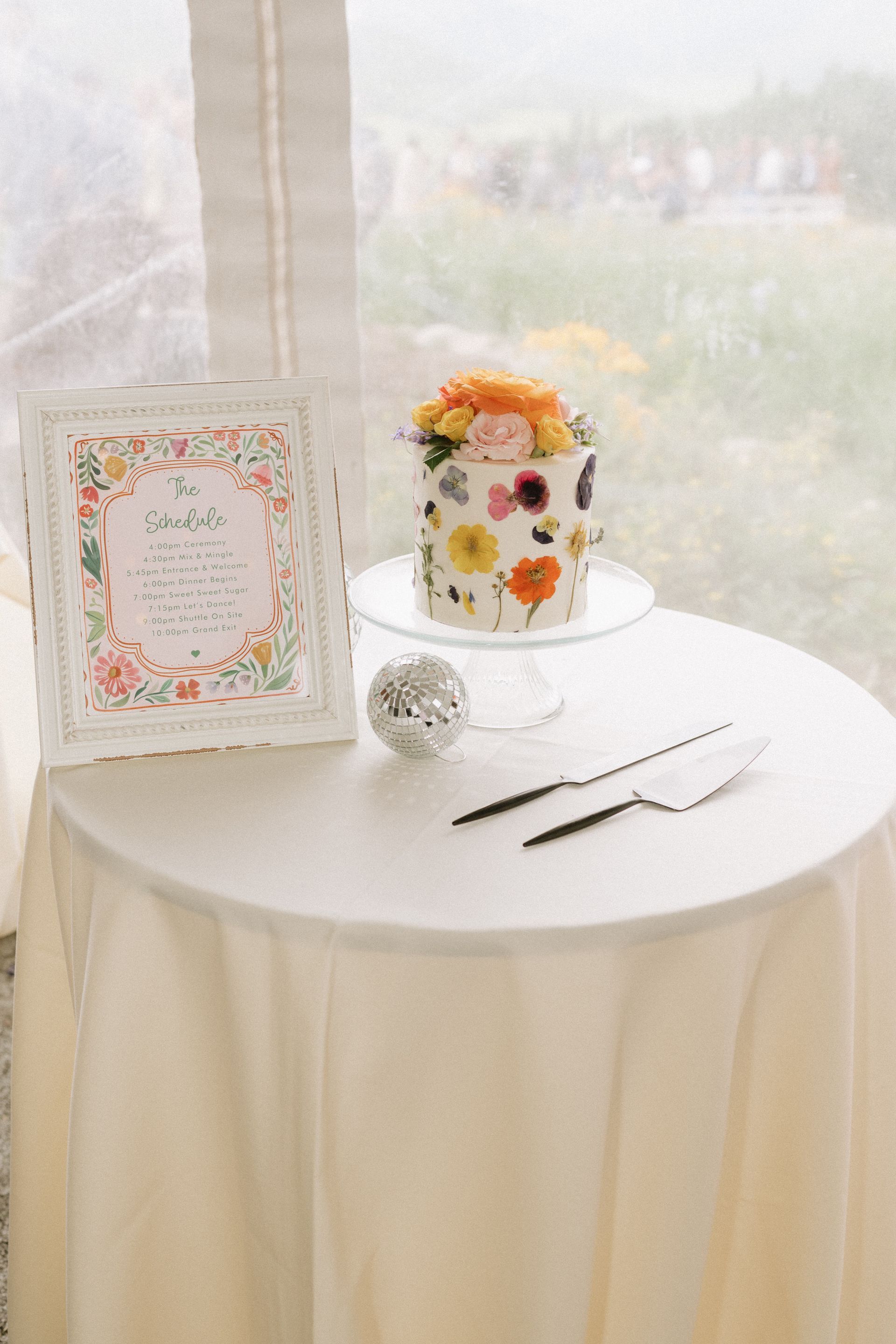 A cake is sitting on top of a table next to a sign.