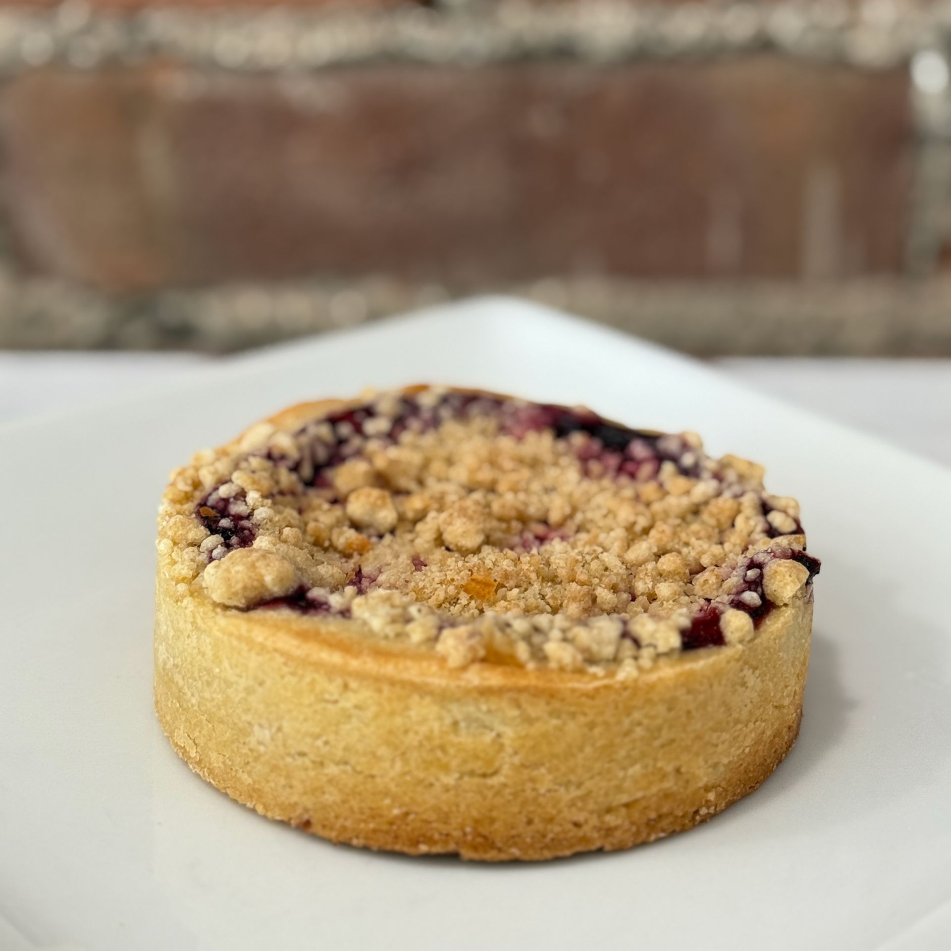 A small pie with crumb topping on a white plate