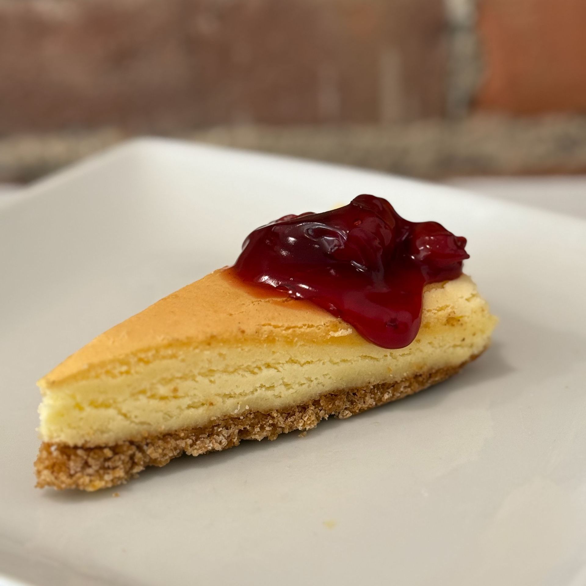 A slice of cheesecake with raspberry sauce on a white plate