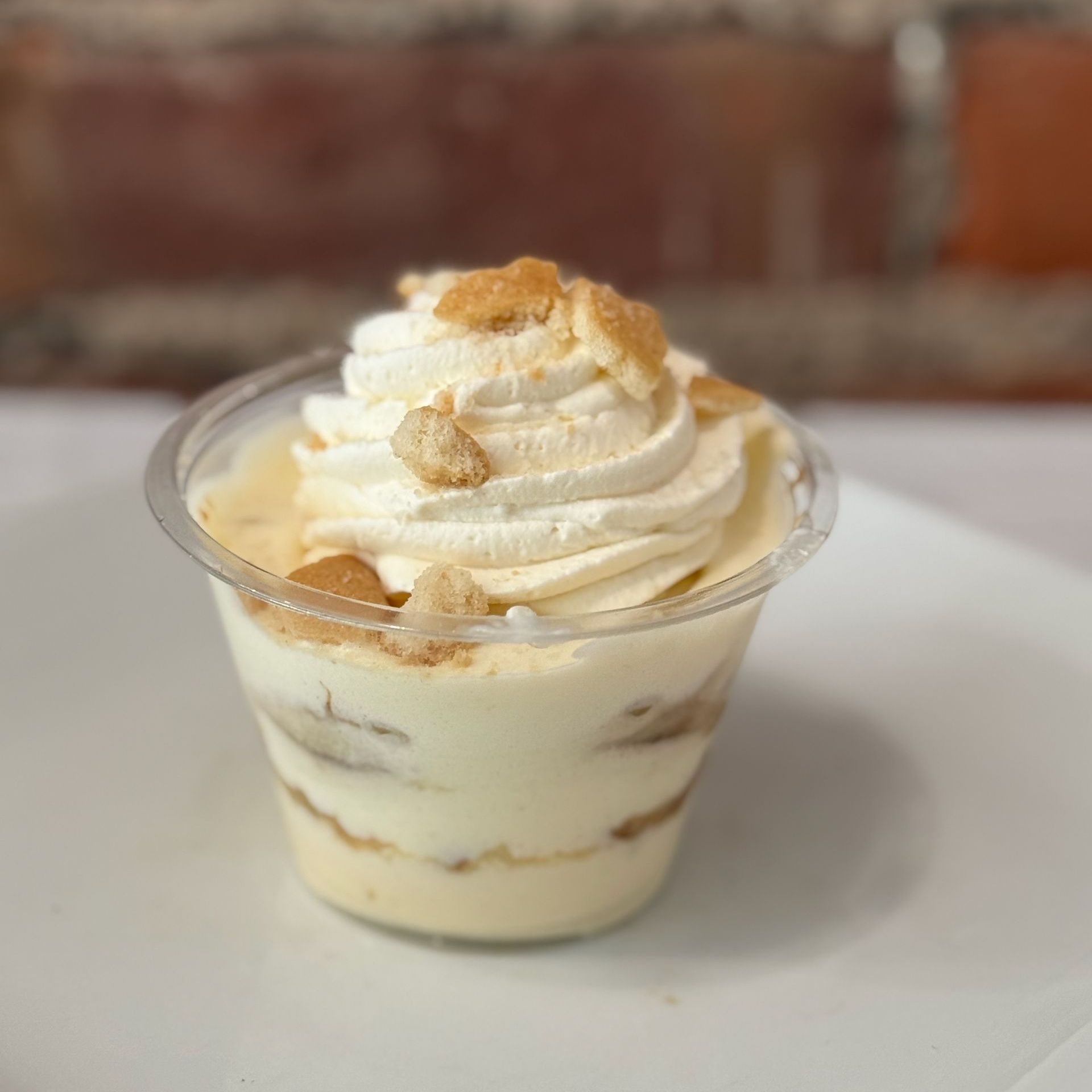 A small cup of dessert with whipped cream and graham crackers on top.