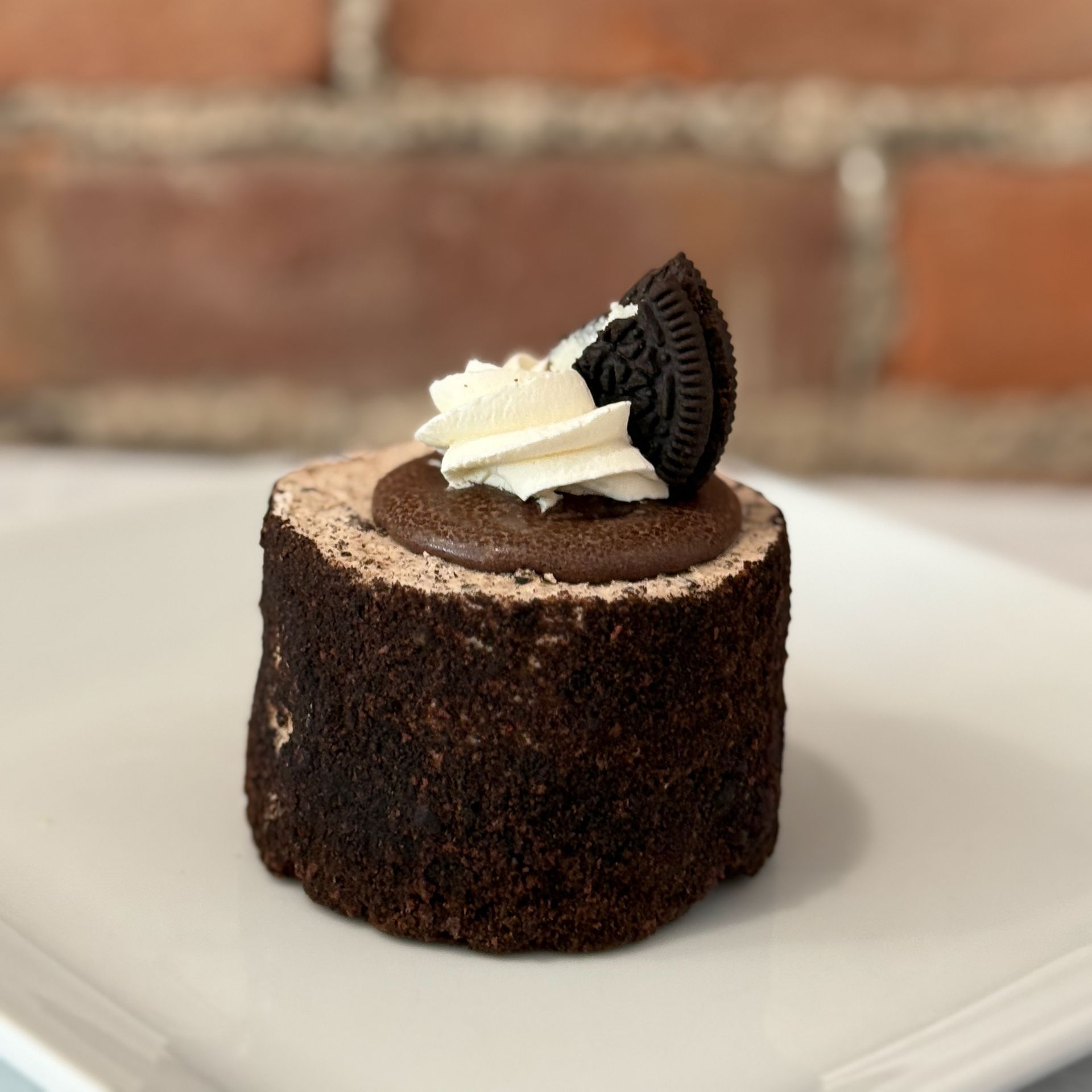 A small chocolate cake with a slice of oreo on top