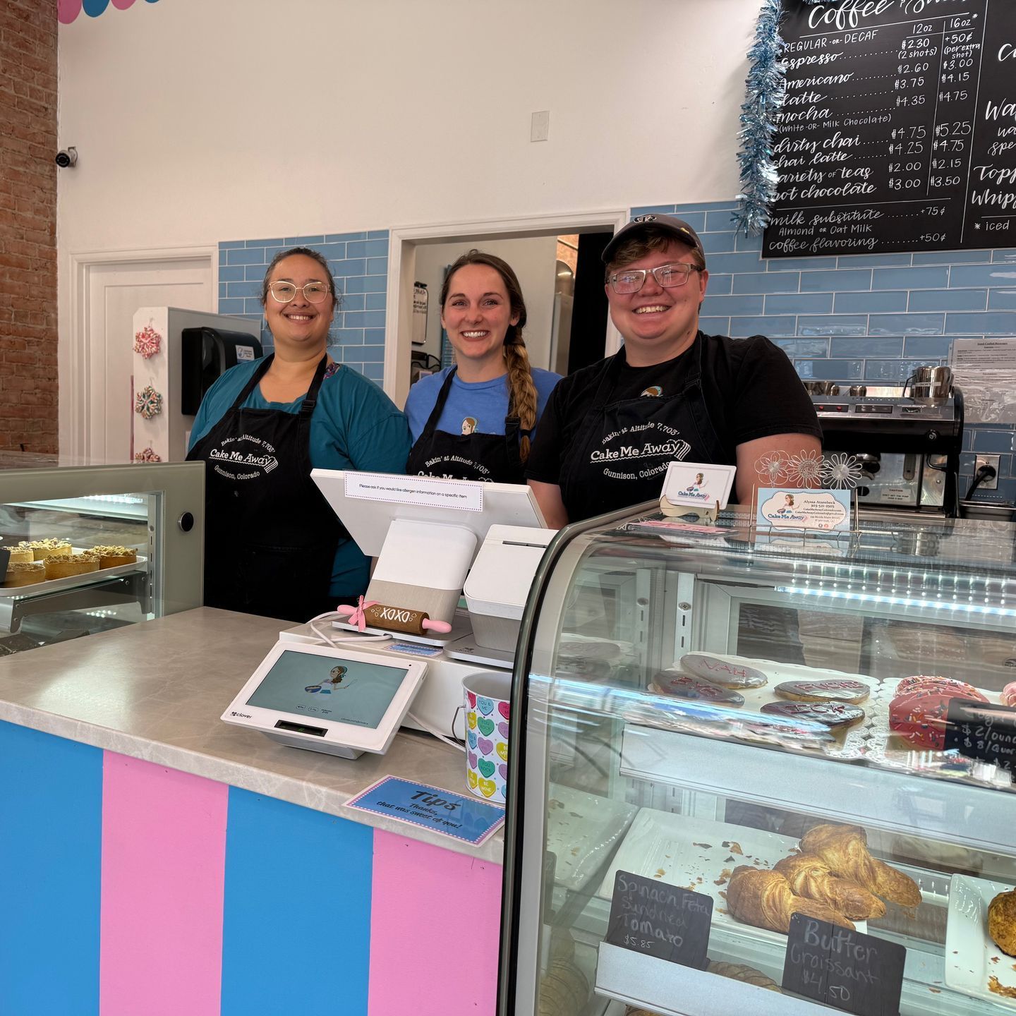Three people are standing behind a counter in a bakery.
