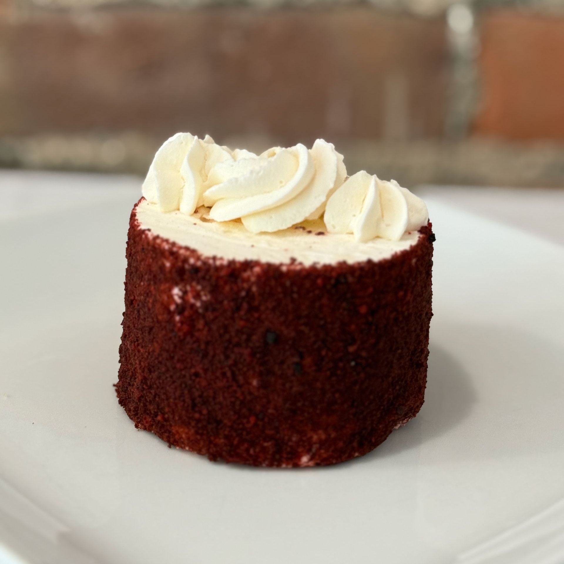 A red velvet cake with whipped cream on top on a white plate