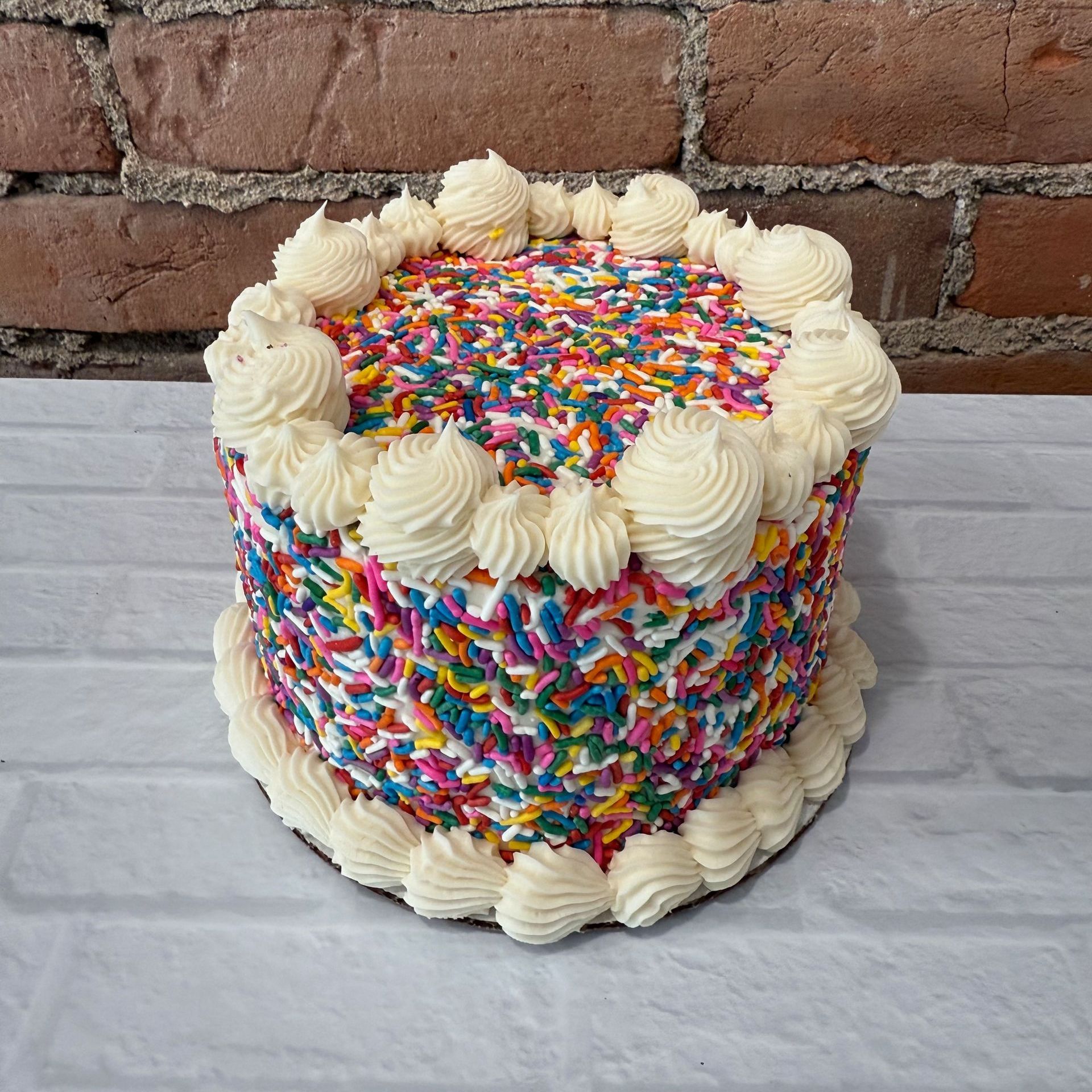 A cake with sprinkles and frosting is sitting on a table.