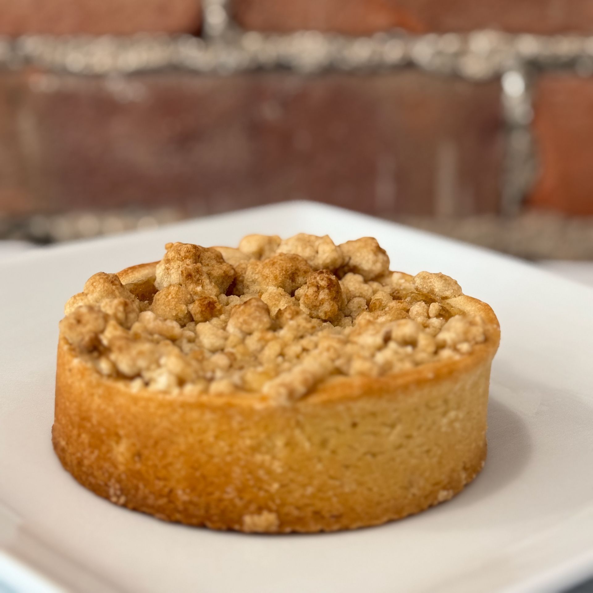 A small pie with crumb topping on a white plate