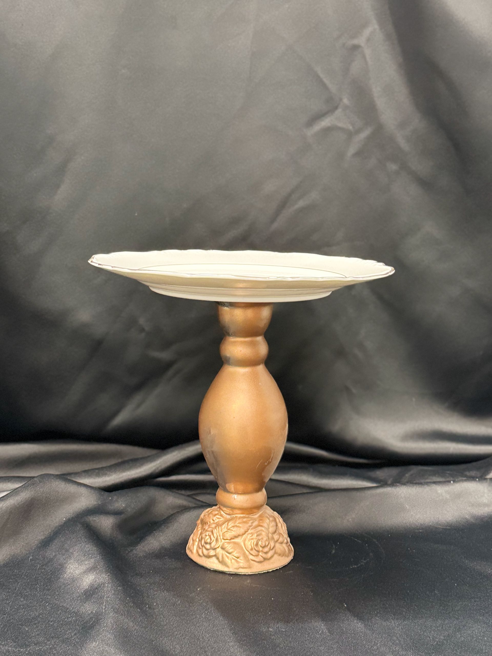 A white plate on a gold stand on a black cloth