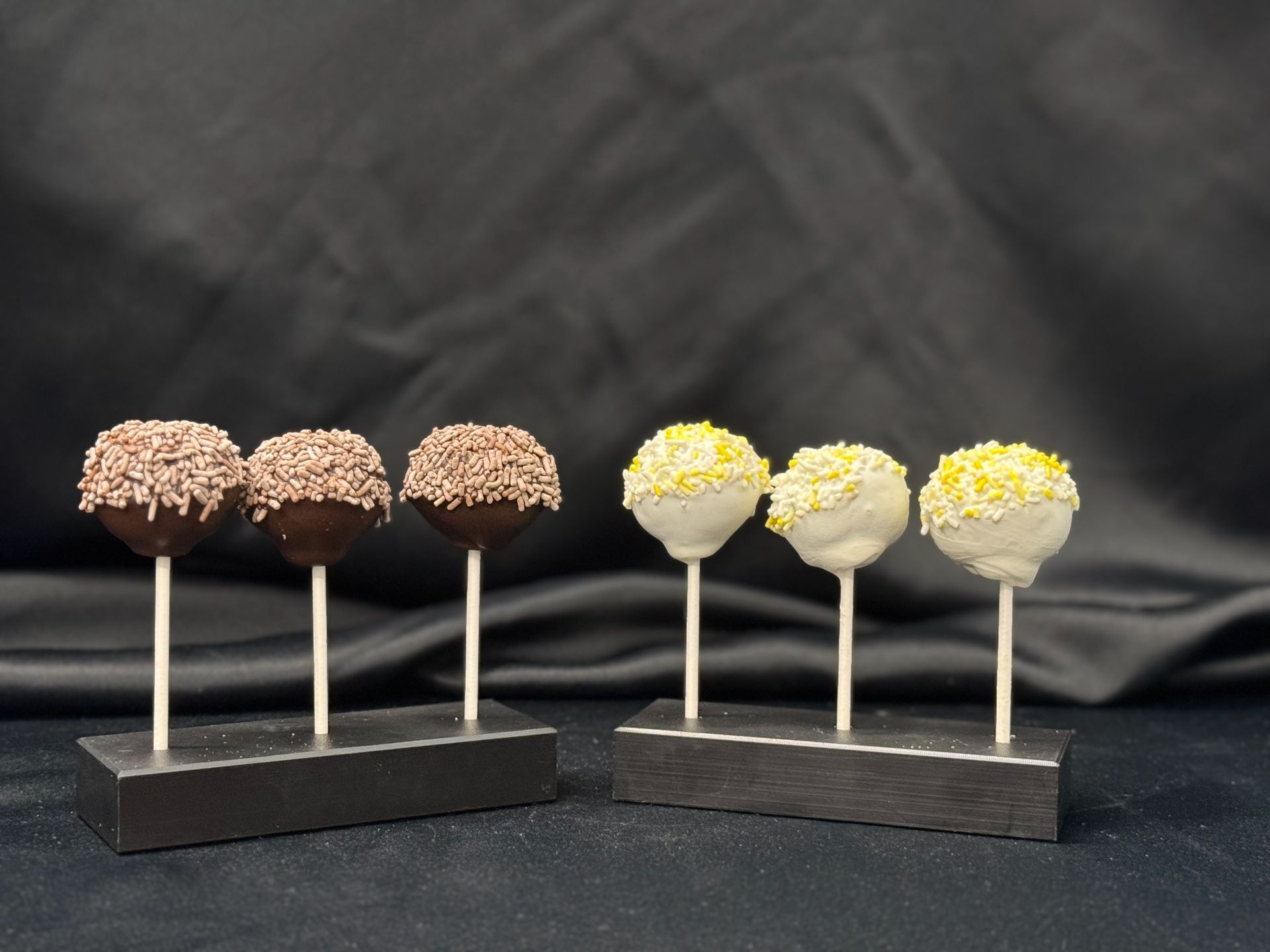 A row of cake pops with different toppings on them