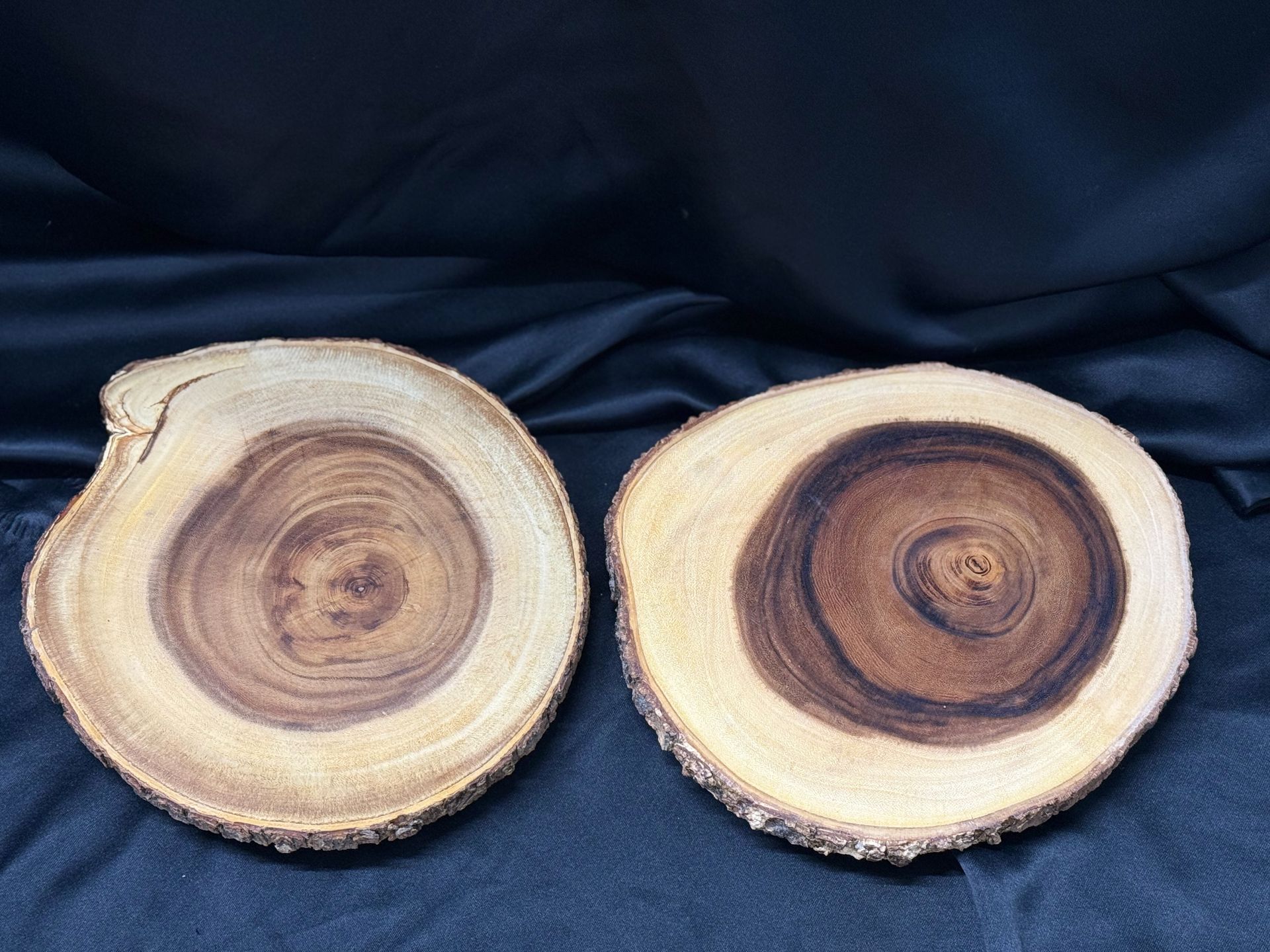 Two slices of wood are sitting next to each other on a black cloth.