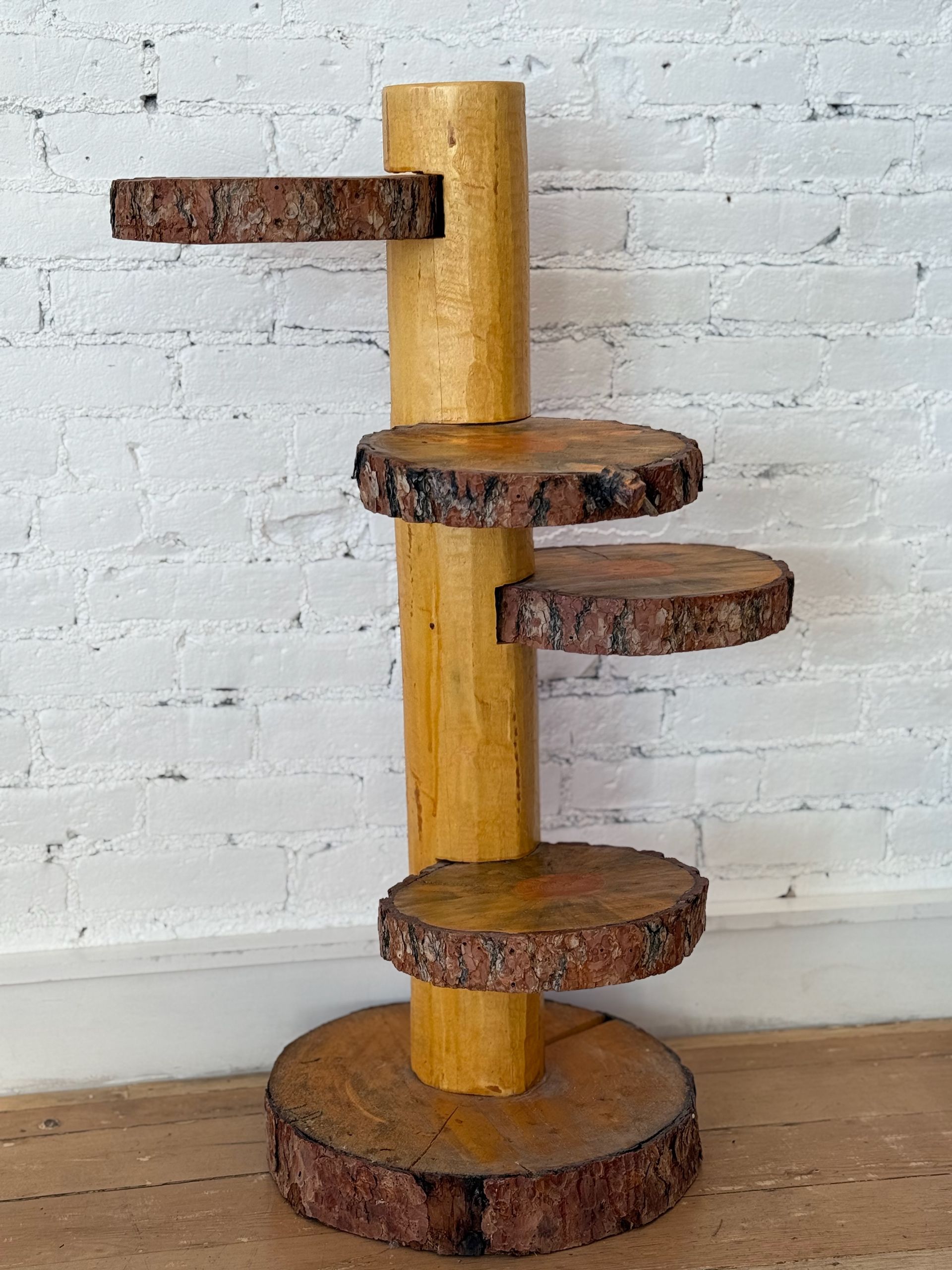 A wooden tree stump shelf is sitting in front of a white brick wall.