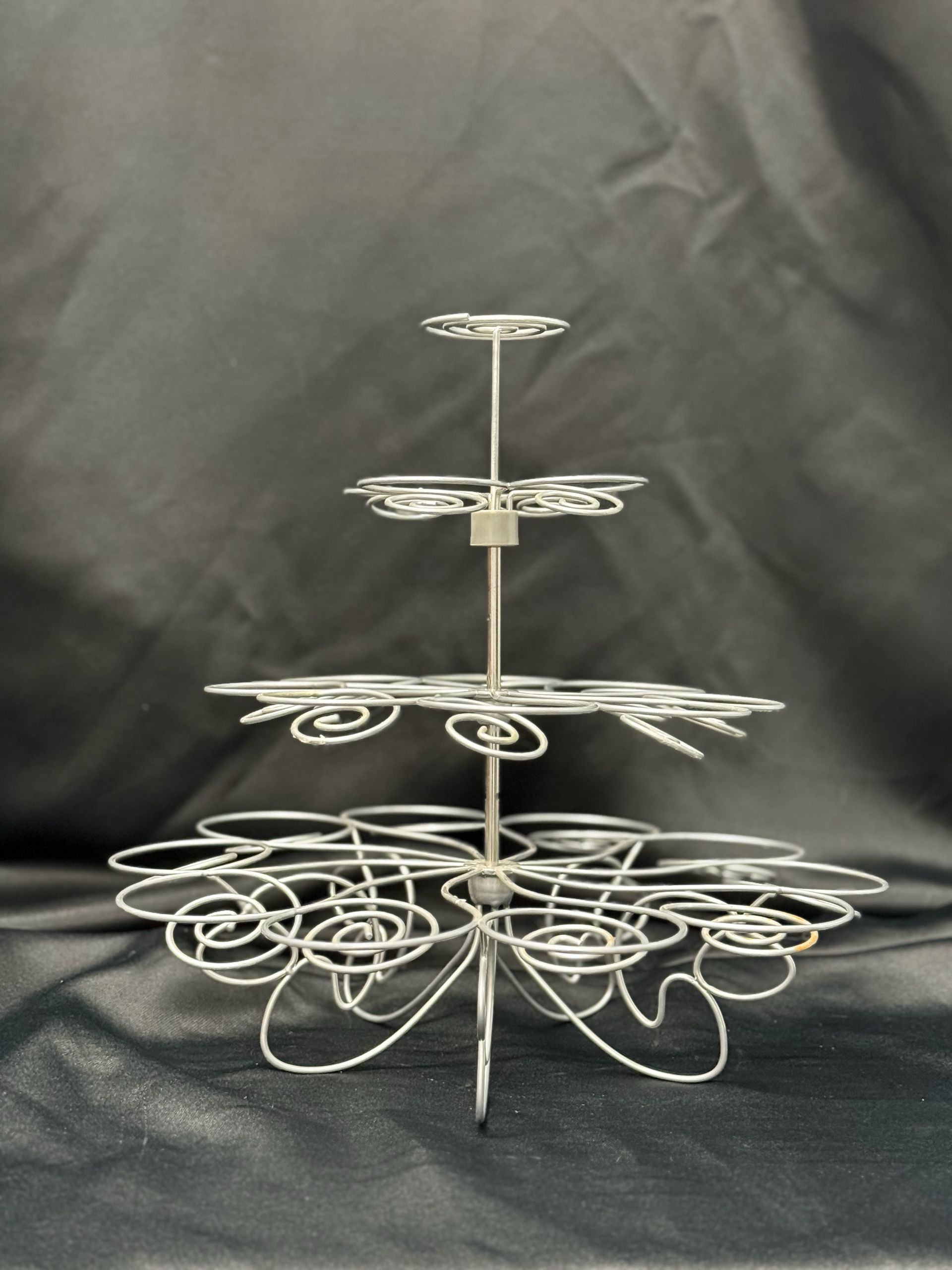 A silver cupcake stand with a black background