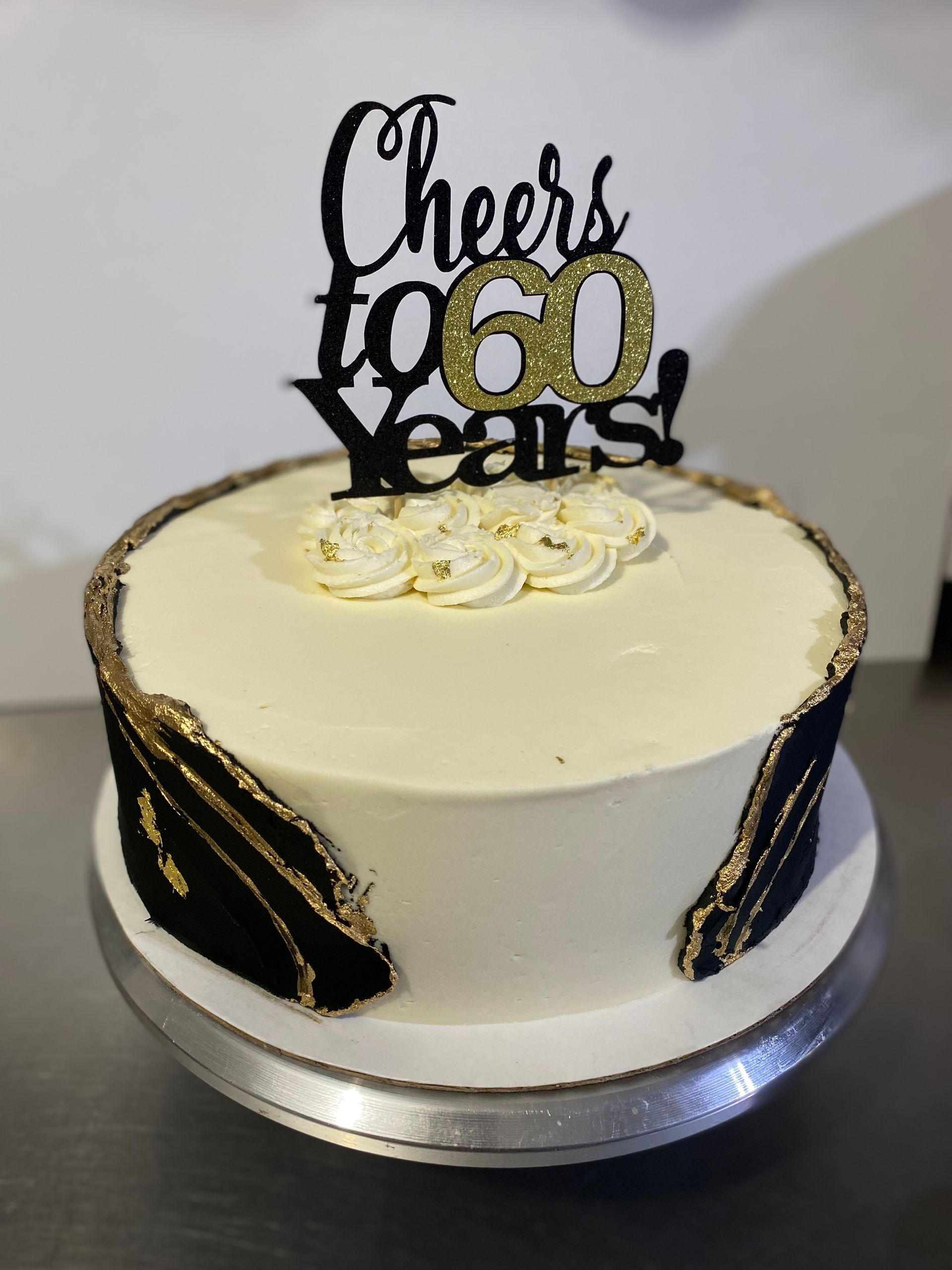 A cake with a topper that says cheers to 60 years