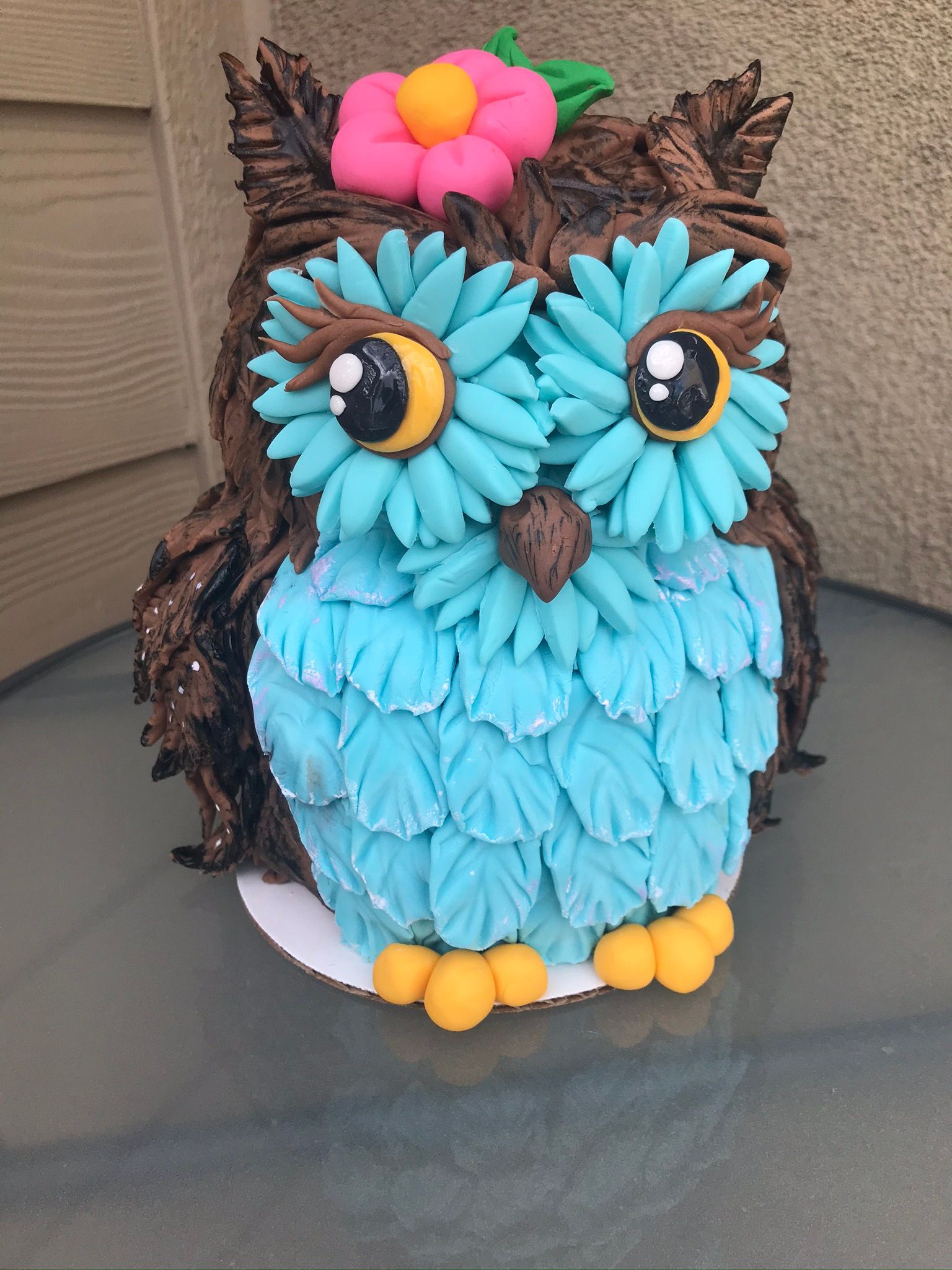 A cake in the shape of an owl with a flower on its head