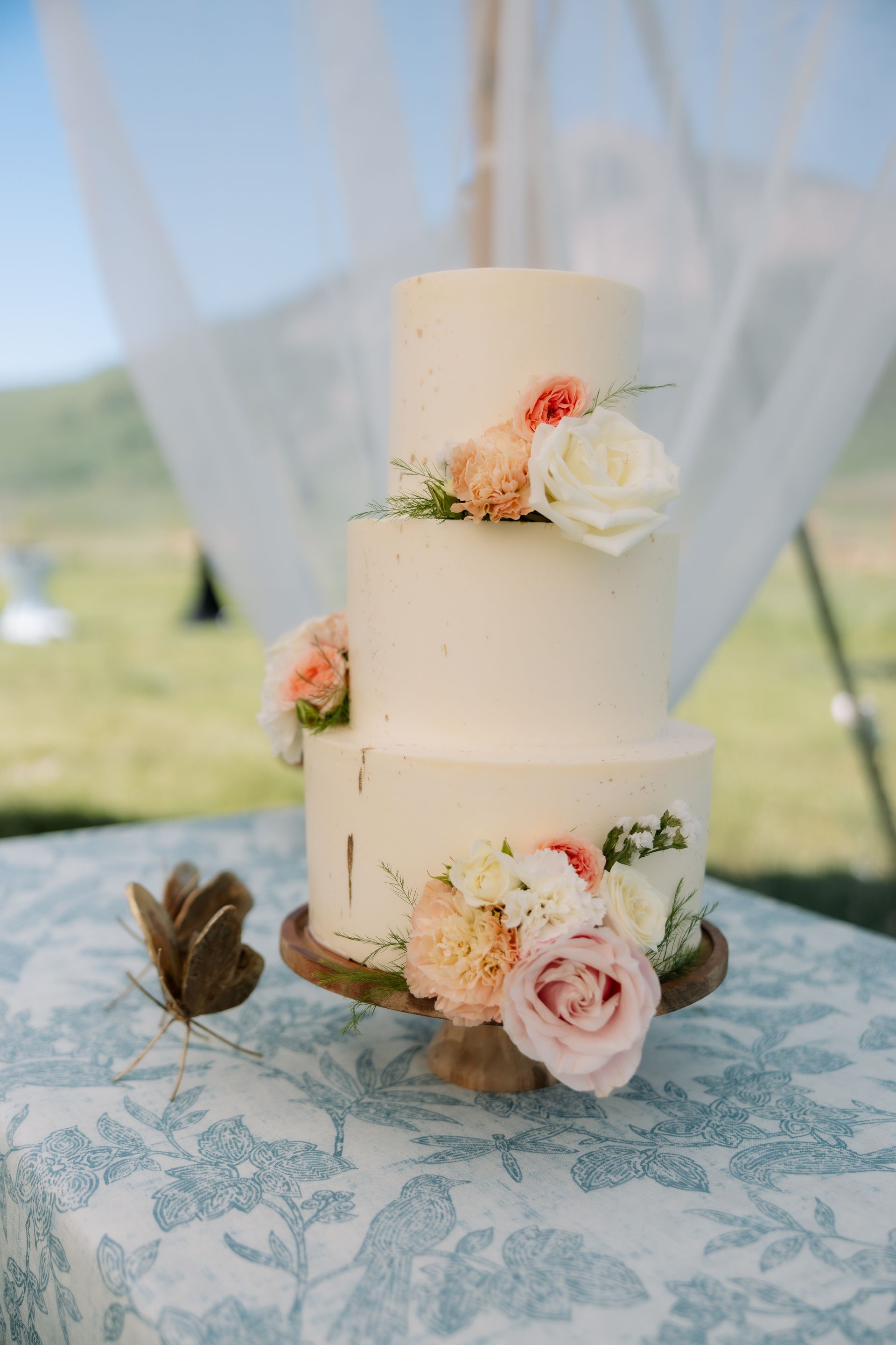 A wedding cake with flowers on it is sitting on a table.
