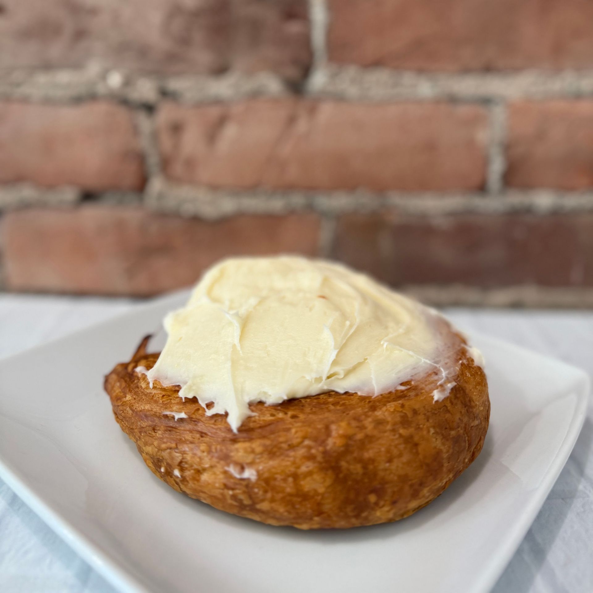 A close up of a cinnamon roll on a white plate.