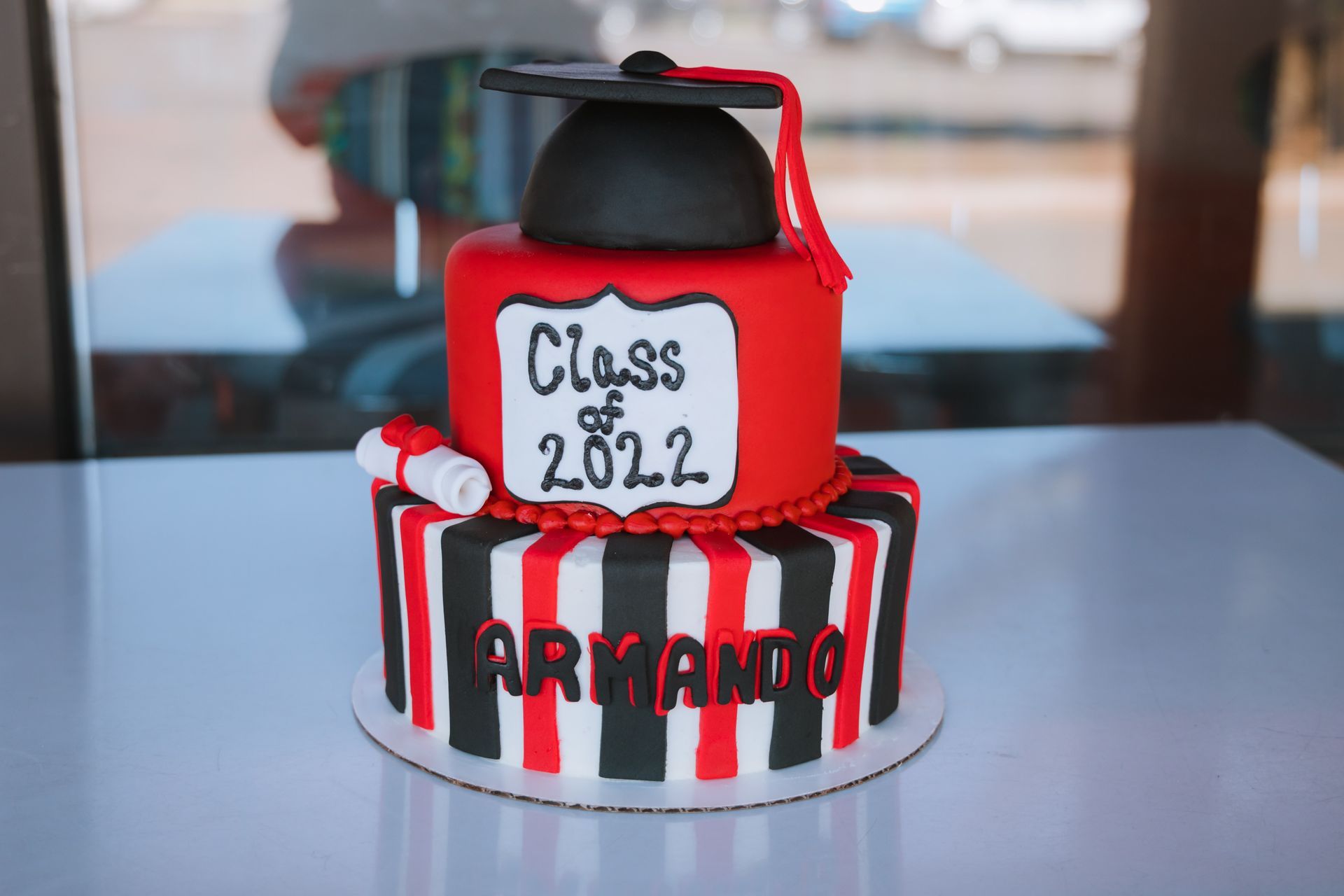 A red and black graduation cake with a graduation cap on top.