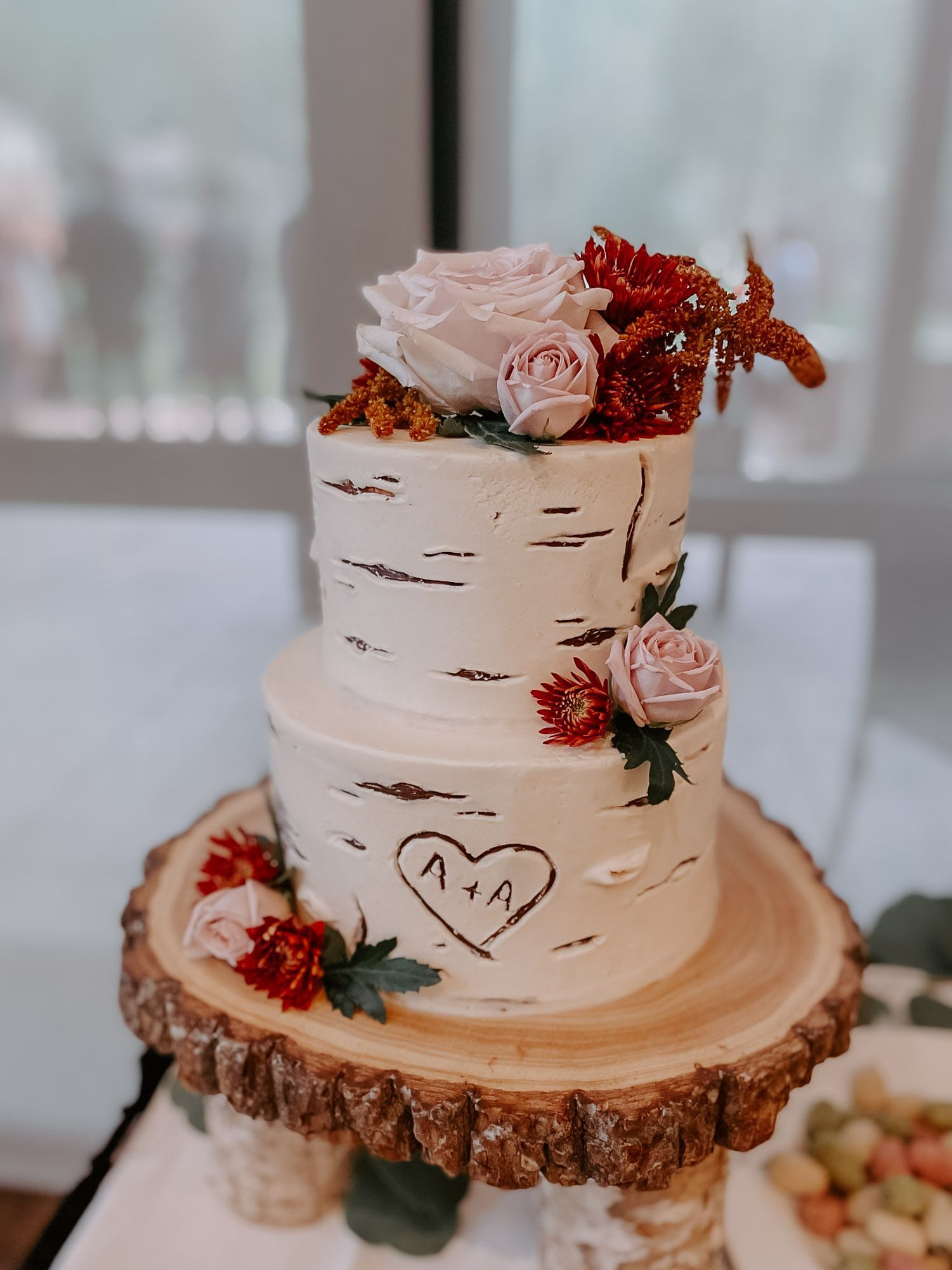 A wedding cake is sitting on top of a wooden slice on a table.