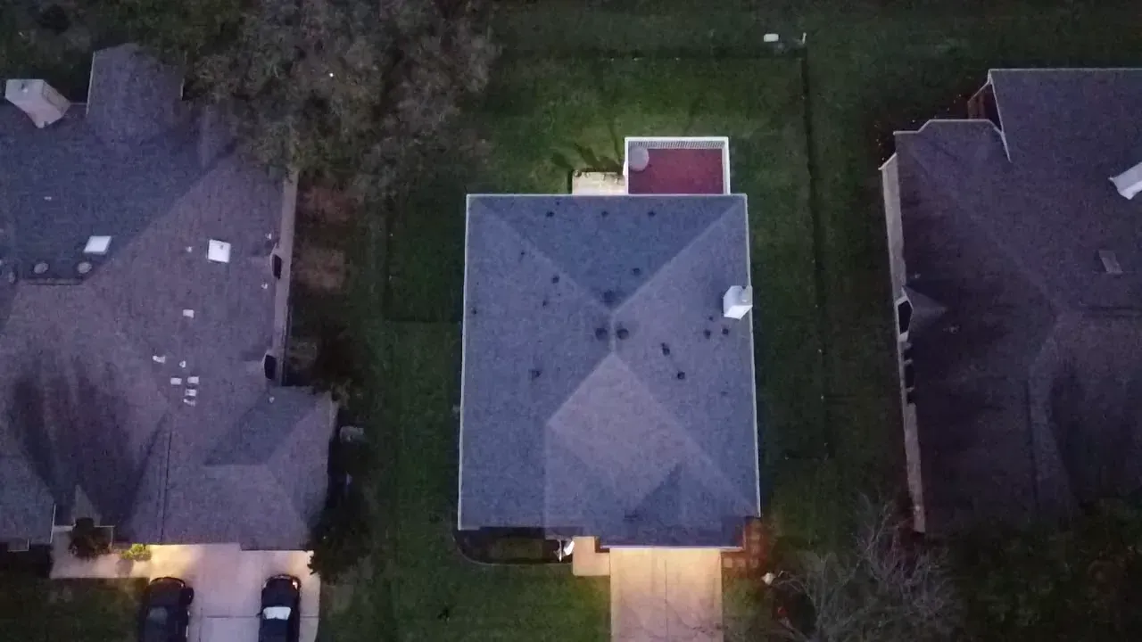 An aerial view of a house at night with a car parked in front of it.