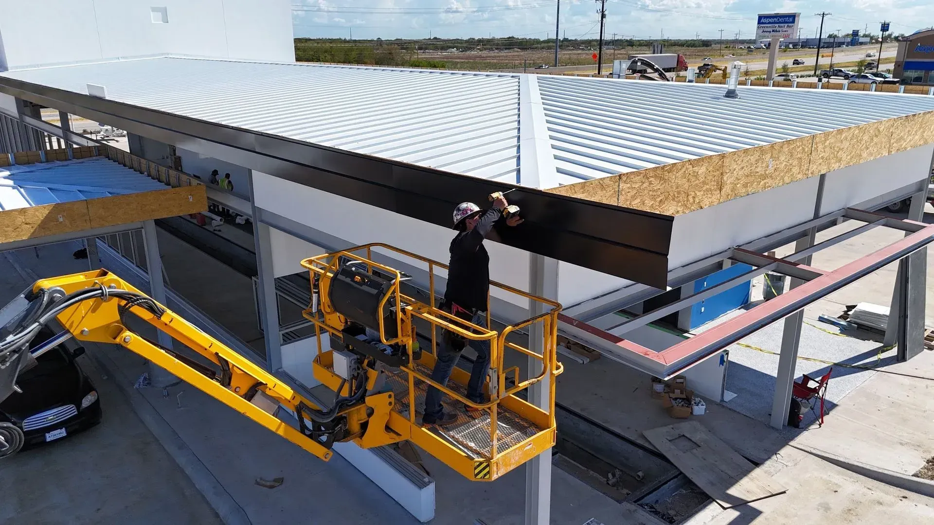A man is working on the roof of a building on a lift.