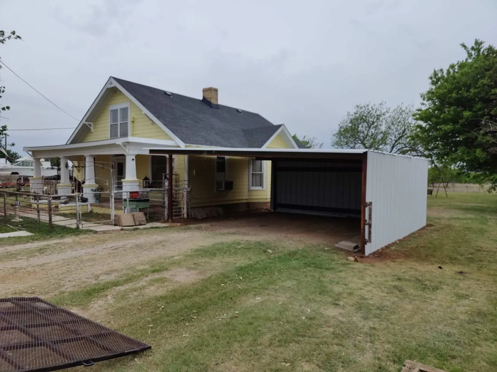 A yellow house with a carport in front of it