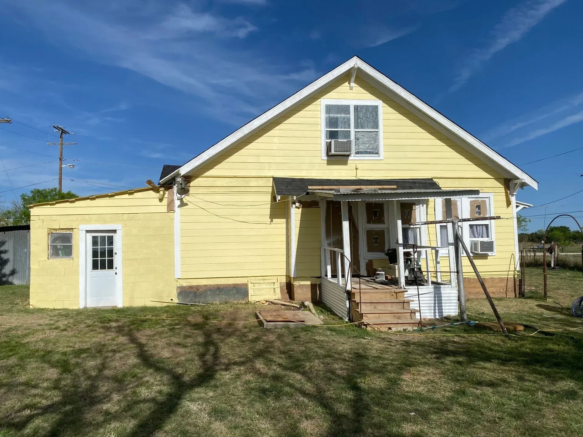 A yellow house with a white roof is sitting on top of a lush green field.