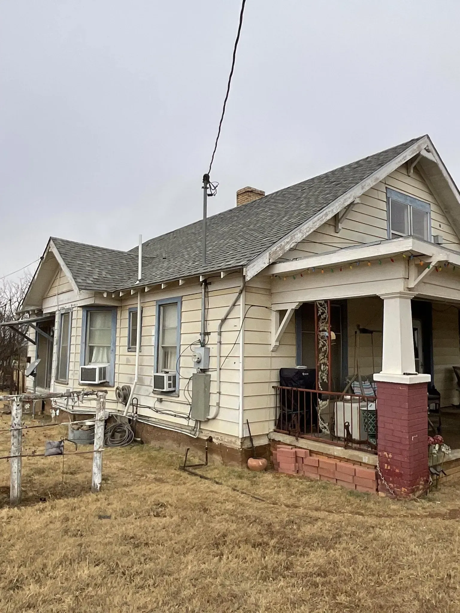 A small white house with a gray roof and a porch.