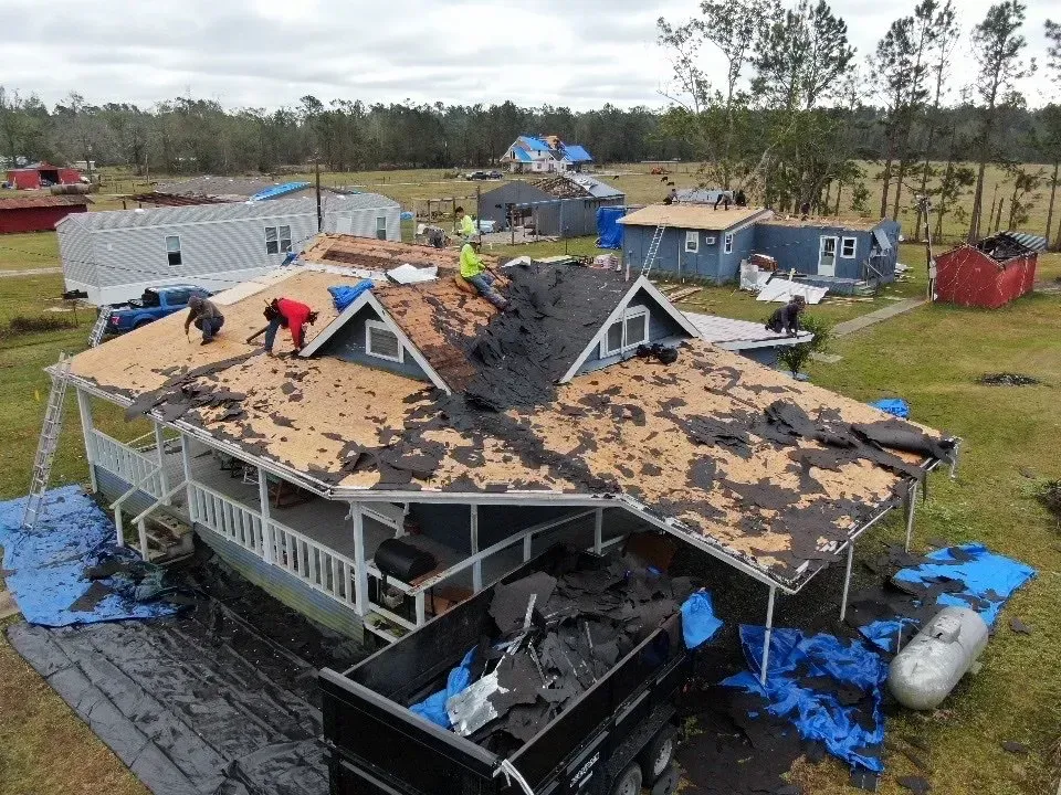 A group of people are working on the roof of a house.