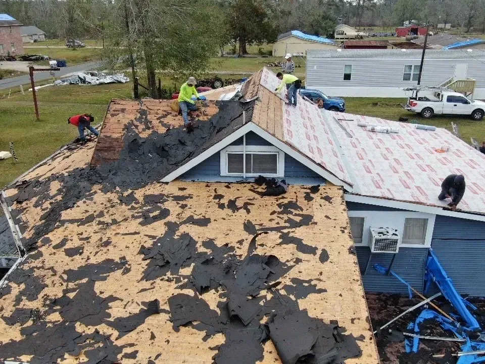 A group of people are working on the roof of a house.
