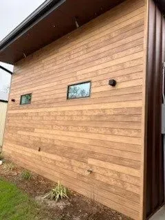 The side of a house with wooden siding and windows.