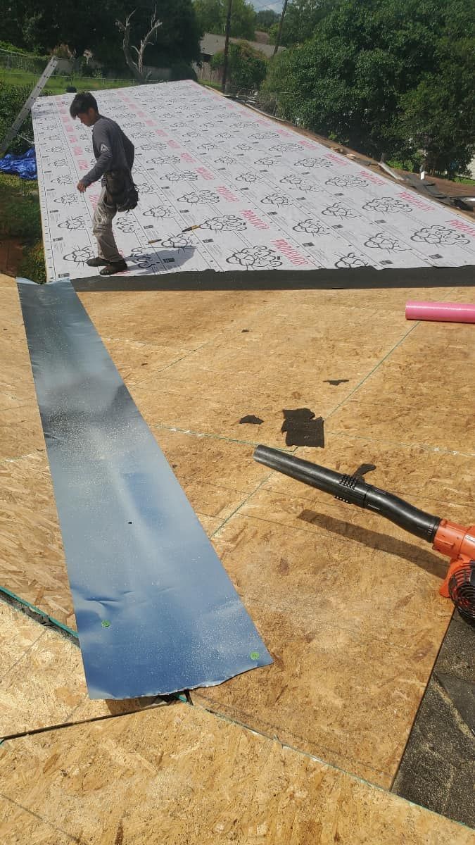 A man is working on a roof with a blower.